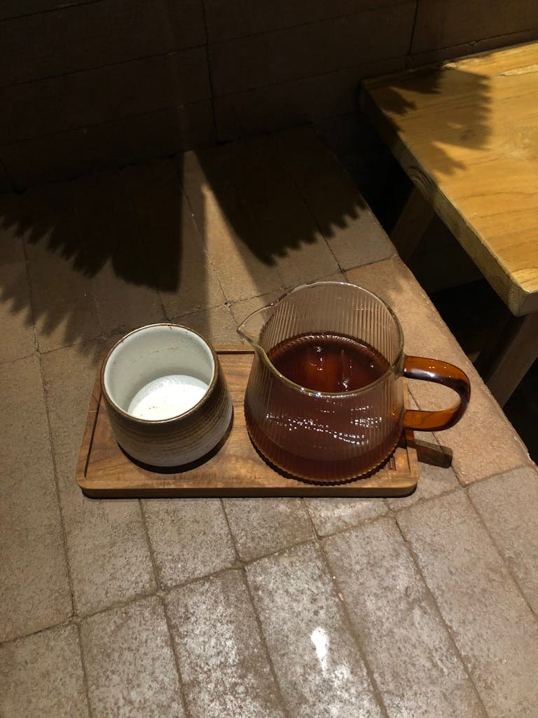 A cozy tea set on a wooden tray casting shadows on a rustic indoor floor.